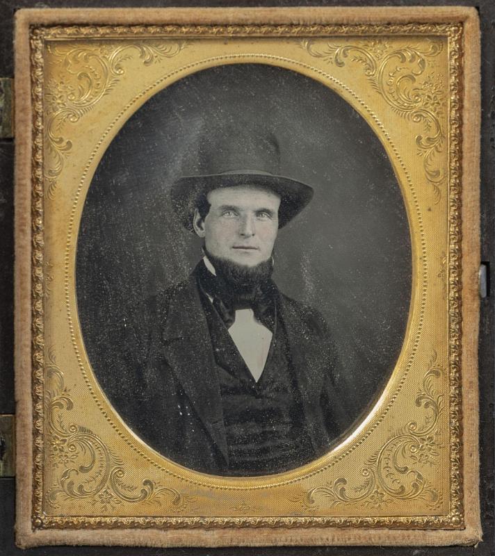Sixth Plate Daguerreotype of a Fireman Seated with Tall Hat. The dag has its original gutta-percha case with raised image of a standing fireman.